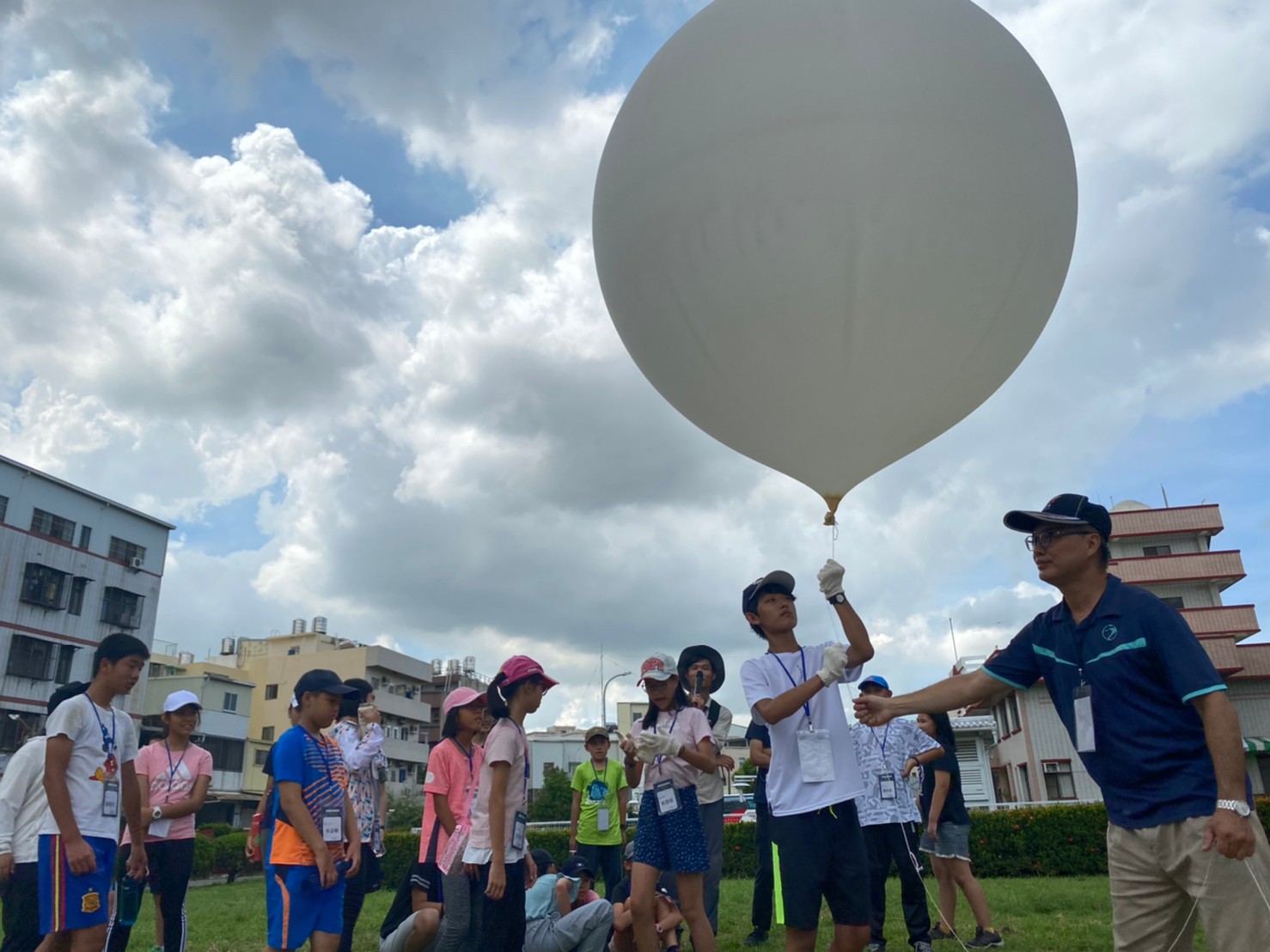 學童參與環境教育活動的照片，畫面中講師正拿著高空探測氣球，向學童進行施放說明。